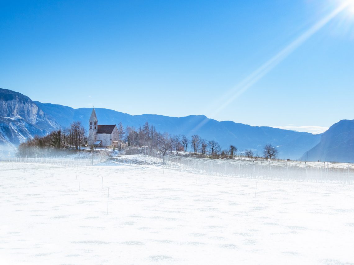 Sonnenstrahl auf Kirche in Graun im Winter